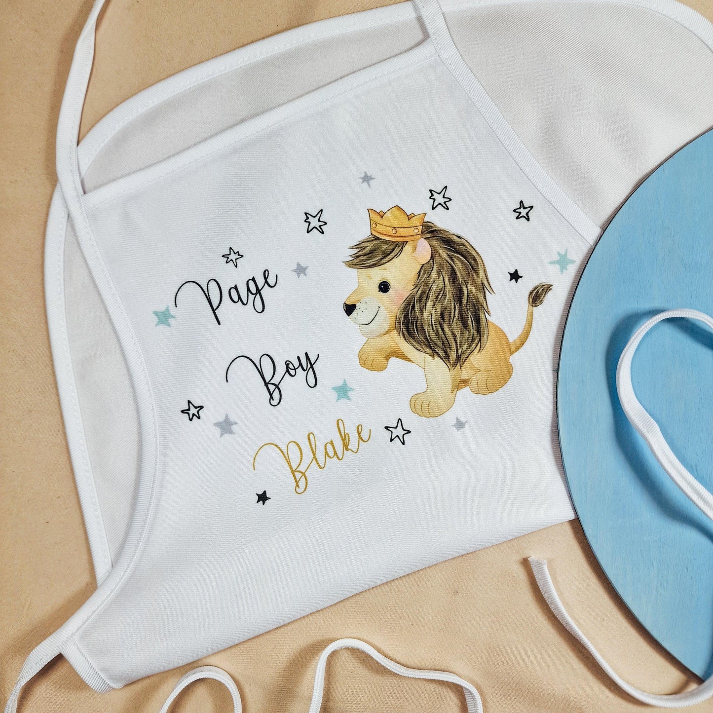 Personalised page boy apron featuring a lion wearing a crown, with custom name option. A cute and practical gift for a page boy, perfect for weddings. The apron is white with a bold lion design and is ideal for keeping outfits clean during wedding festivities.