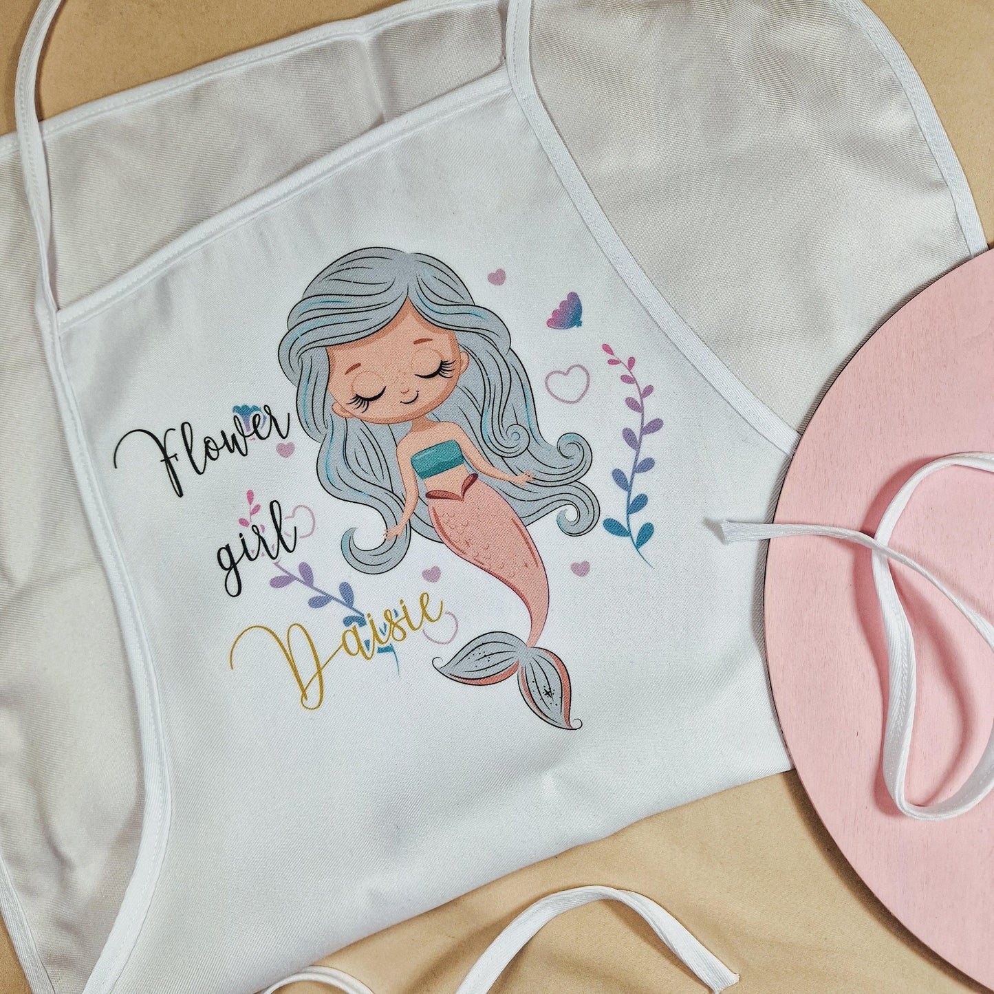 A white apron with 'flower girl' written on and a mermaid design