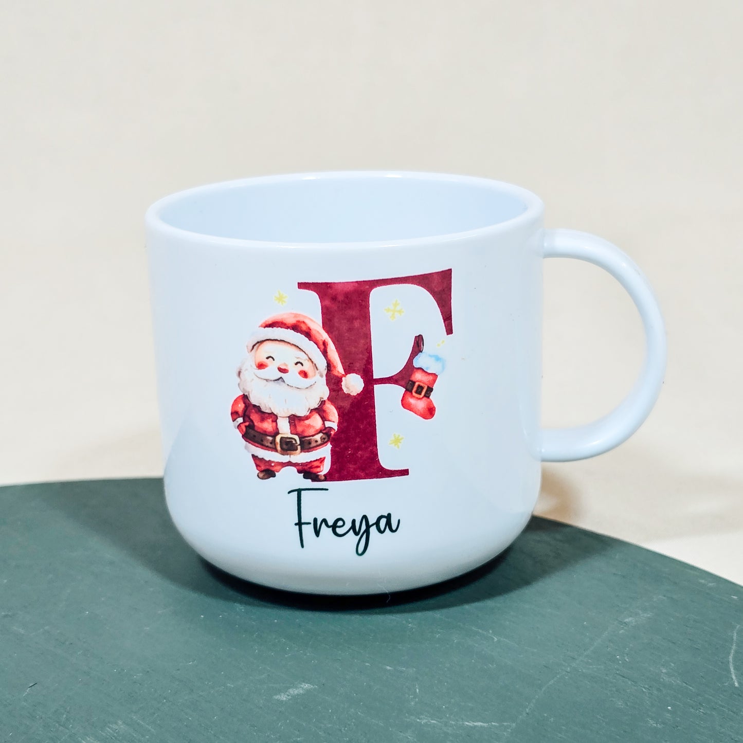 A 6oz polymer children's cup with a festive Santa design, personalised with the child's initial and name, virtually unbreakable.