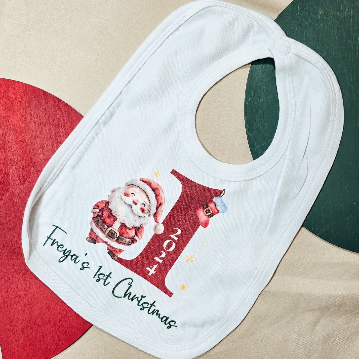 A personalised baby's first Christmas bib featuring a Santa design, a large "1" with the year, and the baby's name, perfect for festive celebrations and keepsakes.