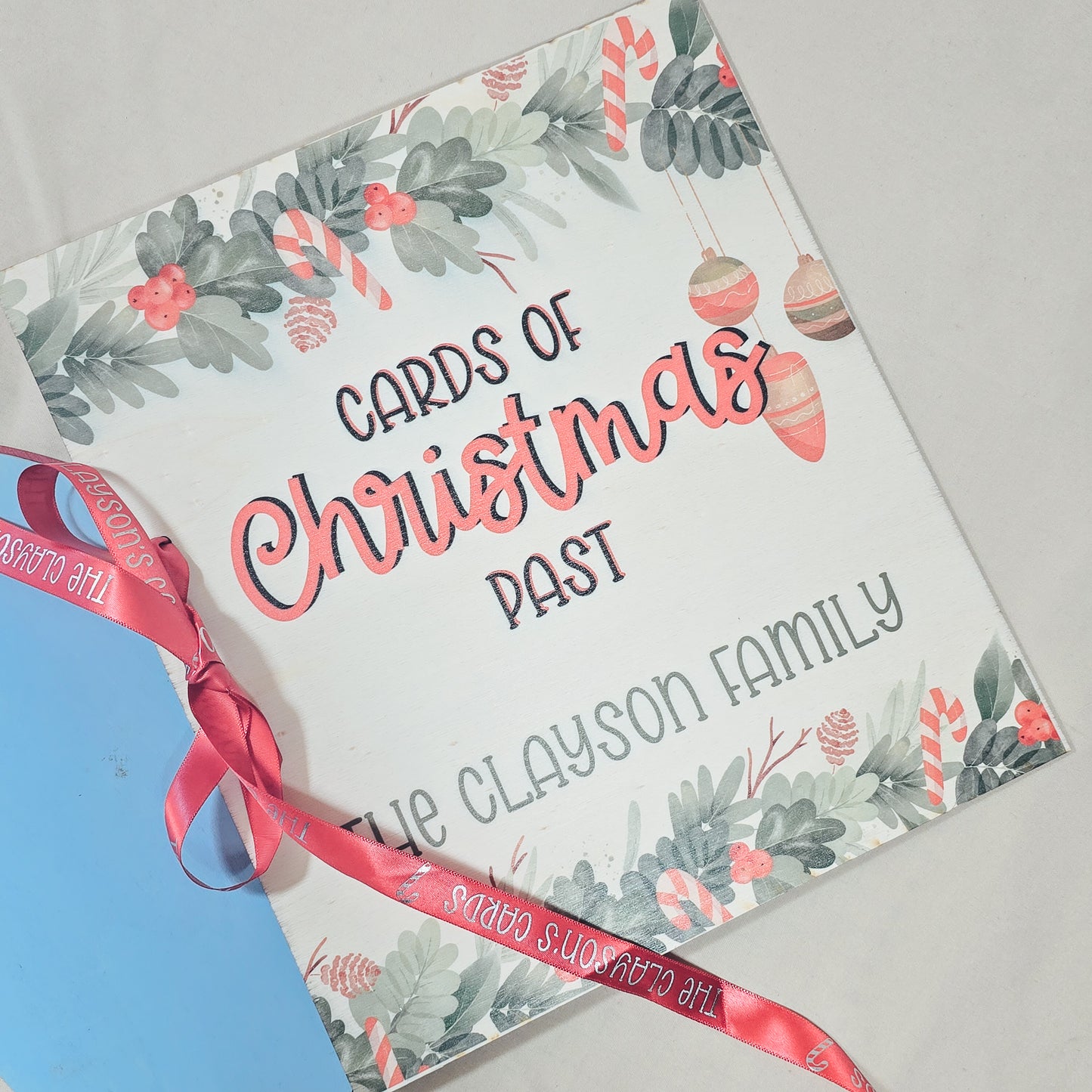 Christmas-themed card packaging with a pink ribbon on a light gray background
