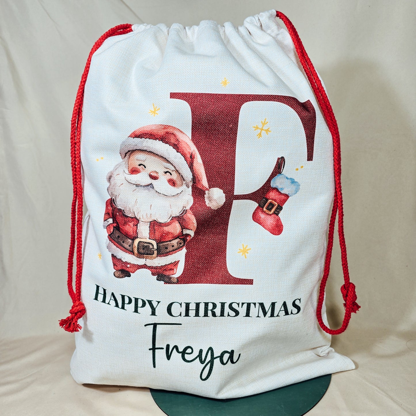 A personalised Santa sack featuring a festive design with an initial and Santa, perfect for holding Christmas gifts and treats.