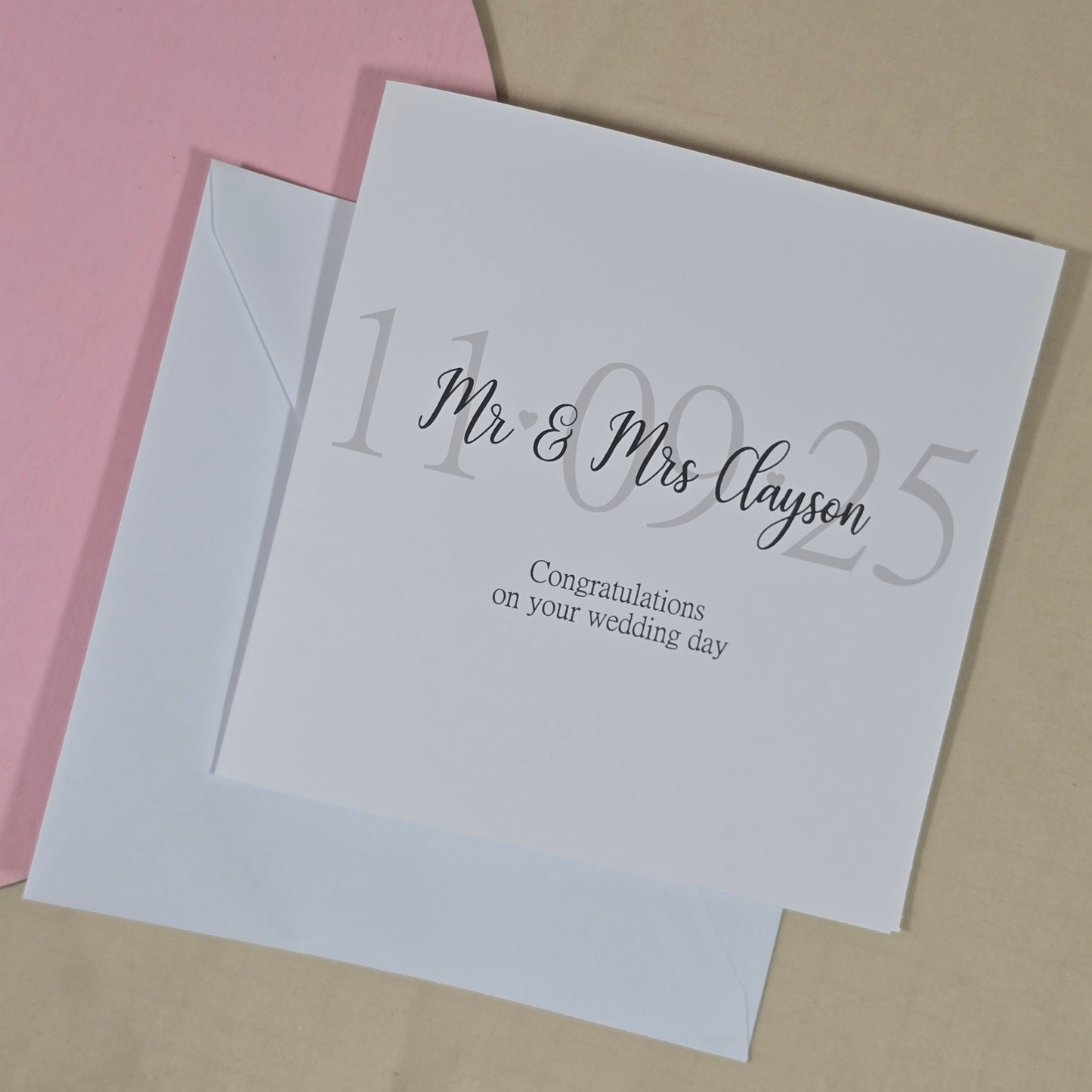 Square wedding card with the message “Congratulations on your wedding day,” featuring the wedding date in the background and the couple’s new name on top.