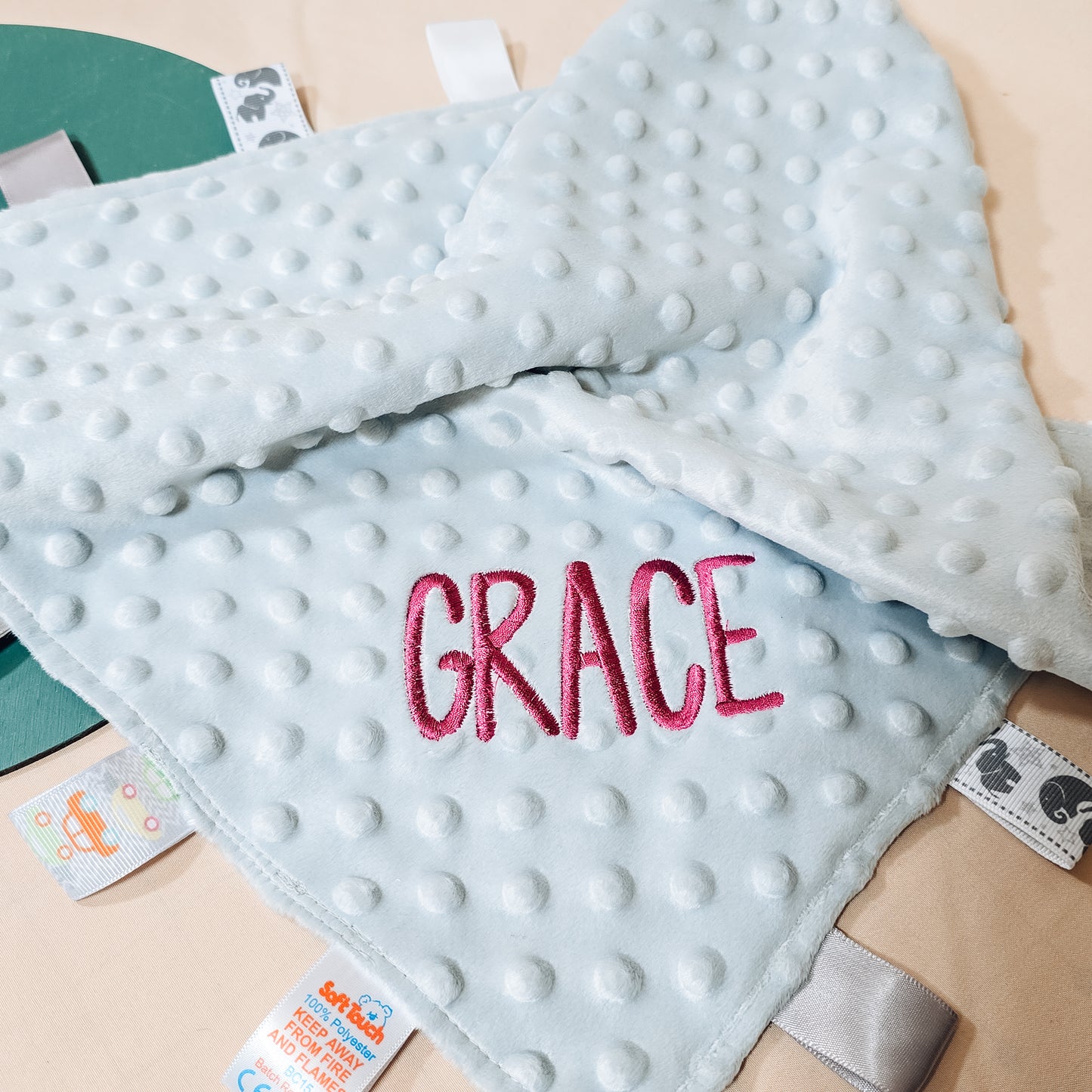 A soft and colourful taggy comforter personalised with embroidered text on the back. Ideal for sensory play and included in the Black Friday sale.