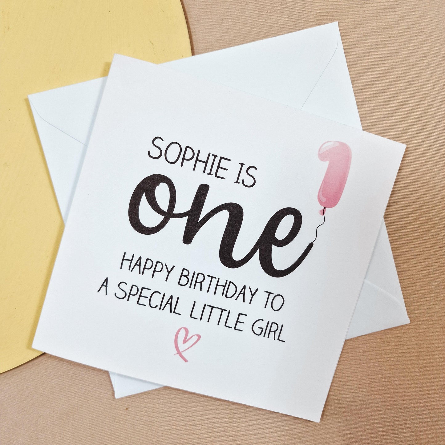 First birthday card featuring a pink balloon in the shape of a 'one' with the message 'Name is one - Happy Birthday to a Special Little Girl.' Customisable with a name and message inside.