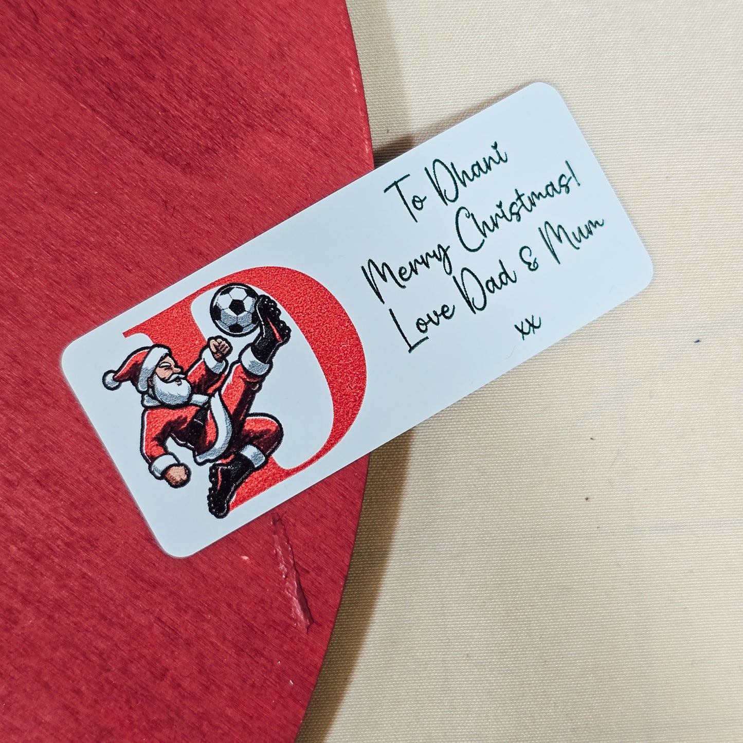 Personalised Santa football sticker featuring Santa playing football, a child’s initial, and a custom message. Approx. 4cm in size, pack of 25