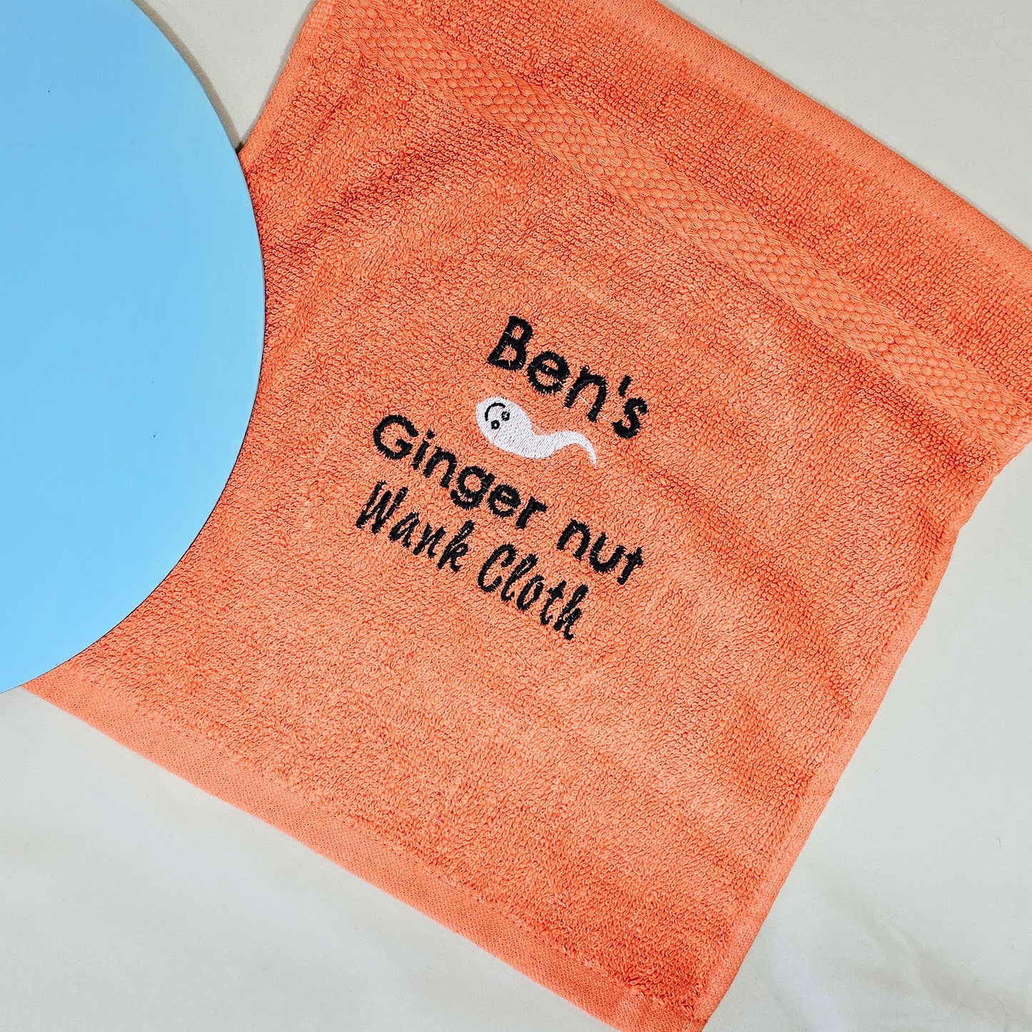 Personalised "Name's Ginger Nut Wank Cloth" with humorous embroidery, displayed on a soft fabric background.