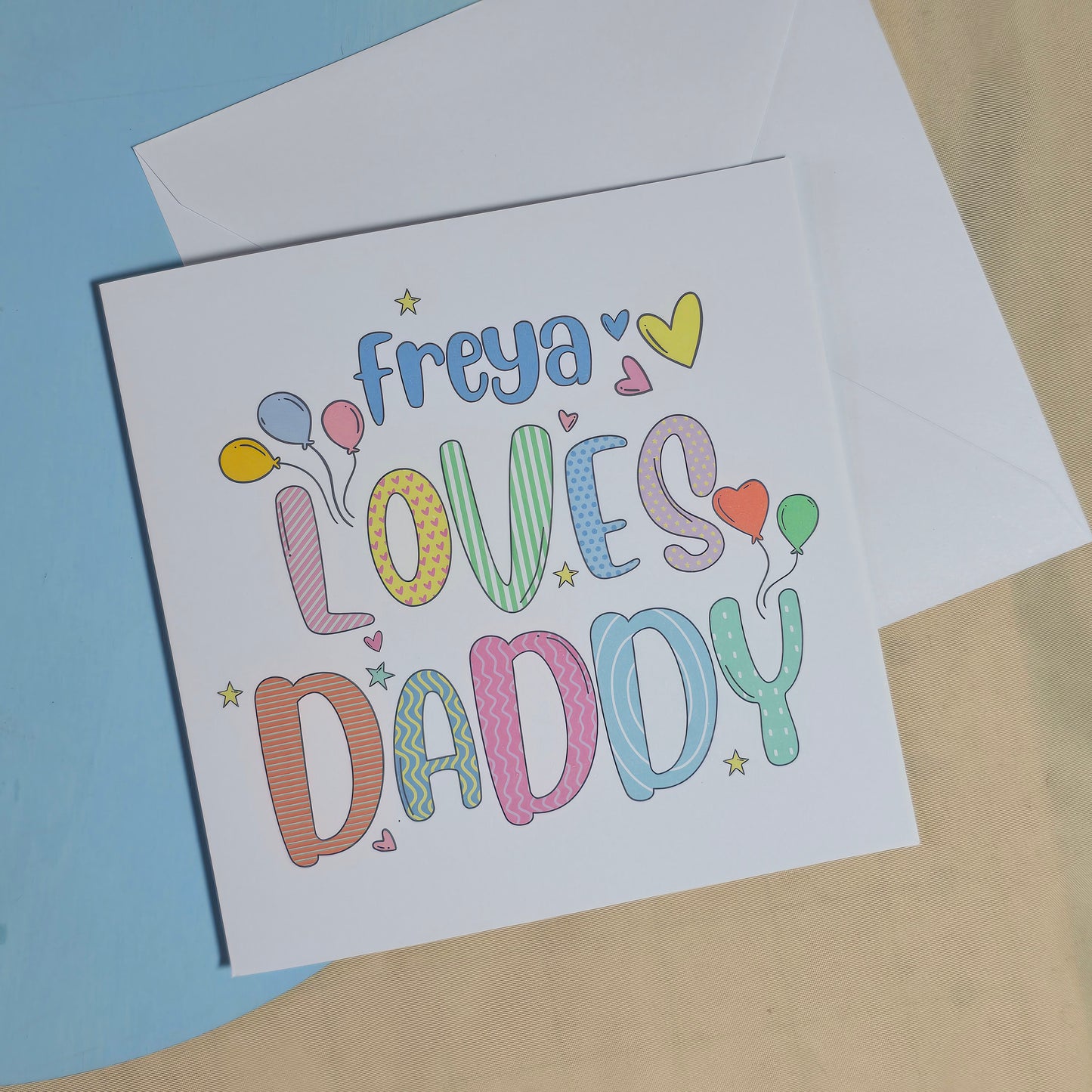 Greeting card with colorful text and envelope on a light brown background