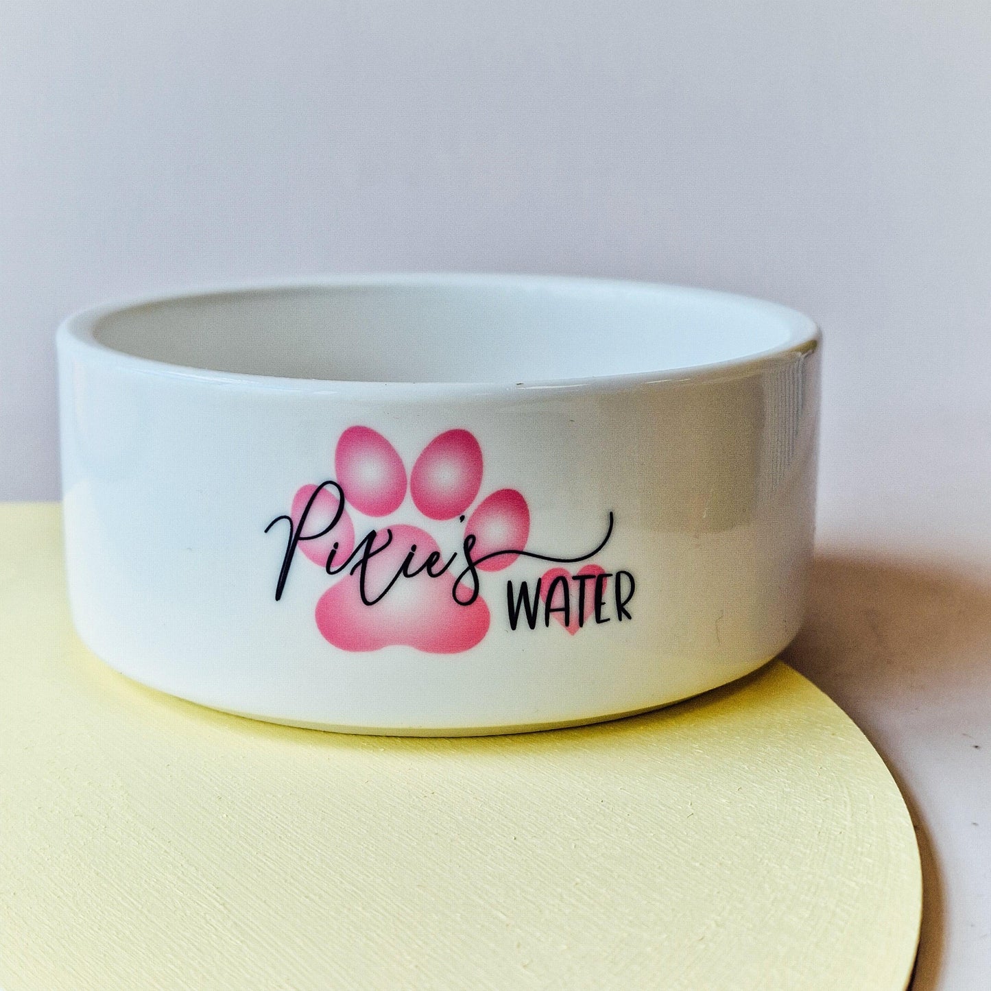 Pet bowl featuring a pink paw print and heart design, personalised with the pet’s name, with options for 'food' or 'water,' available in small, medium, and large sizes.