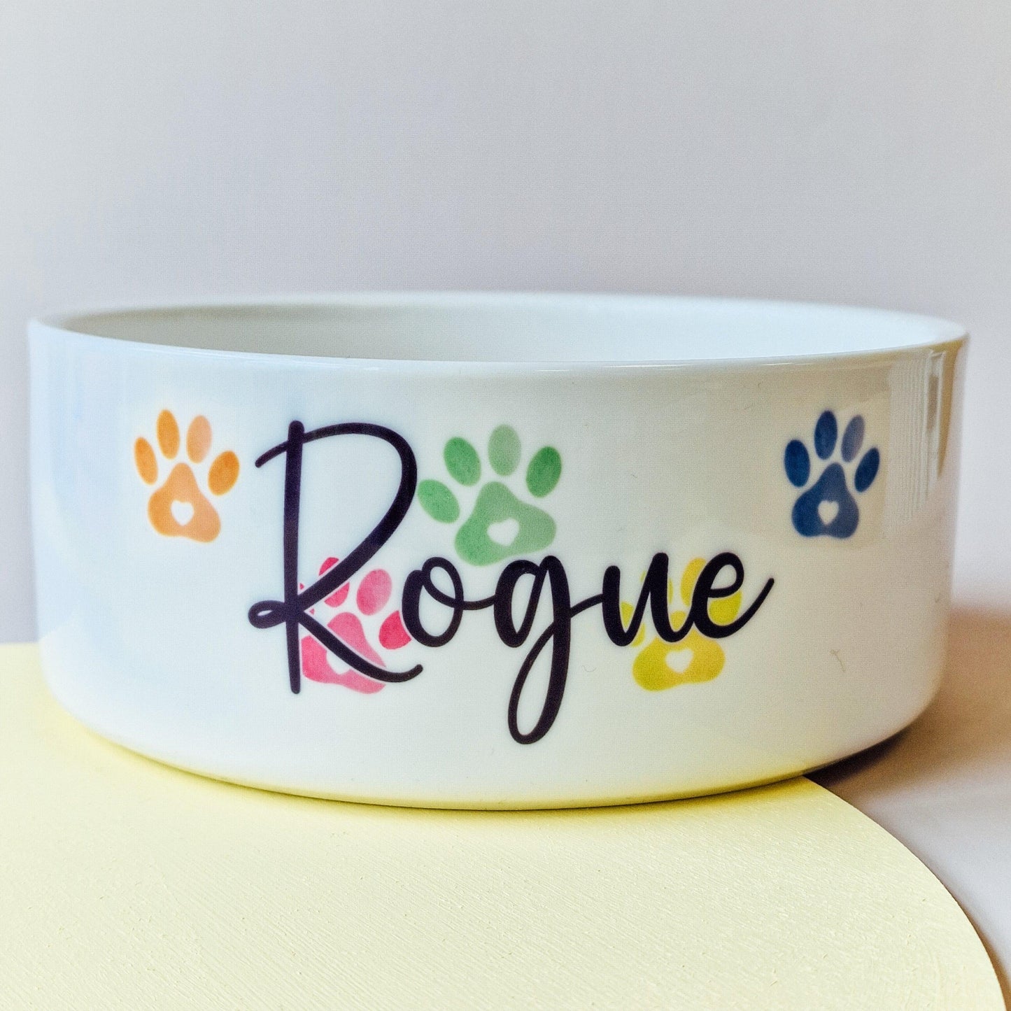 Pet bowl with rainbow-coloured paw prints behind a personalised name, available in small, medium, and large sizes, adding a vibrant touch to your pet’s feeding time.