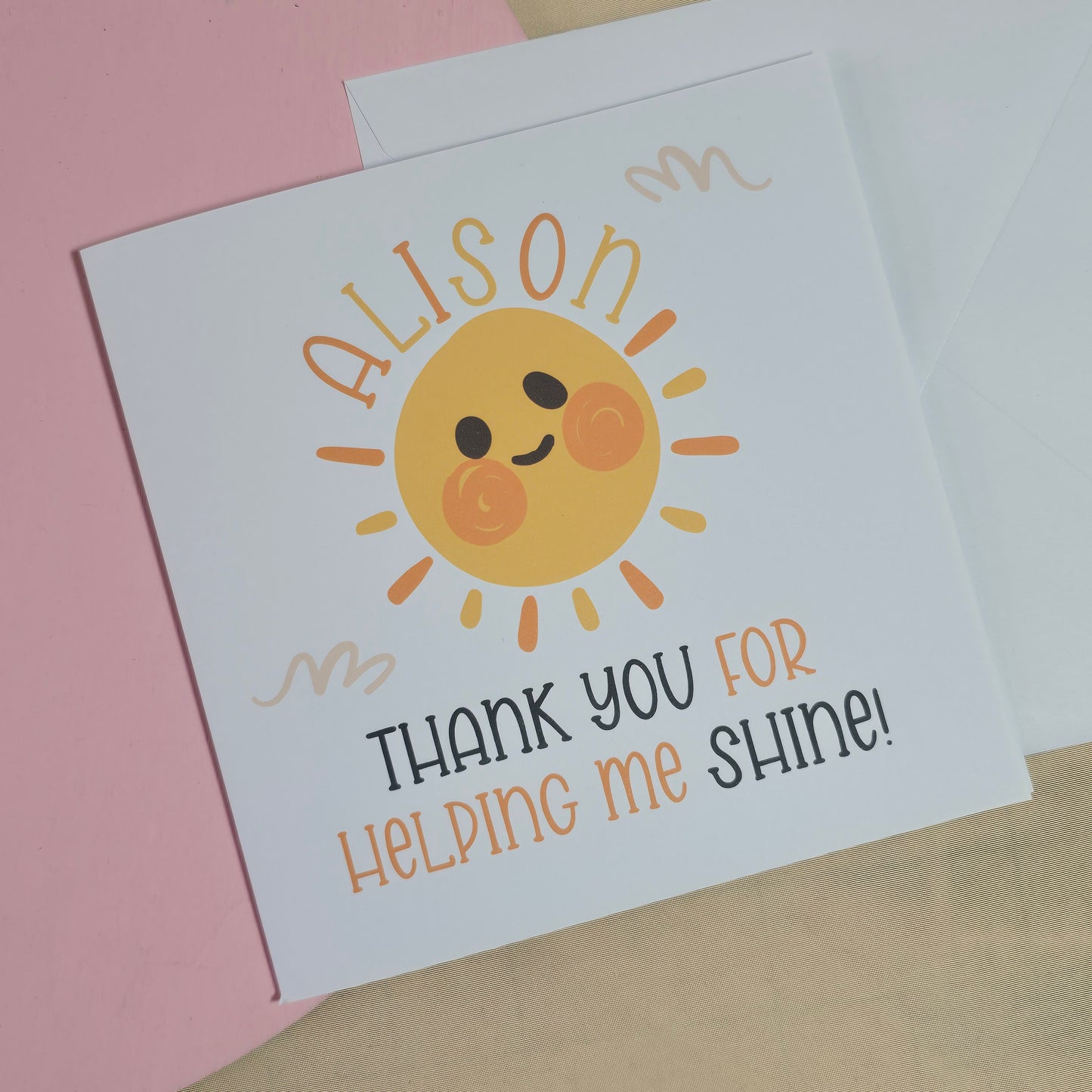 Greeting card with a sun illustration and text on a pink surface