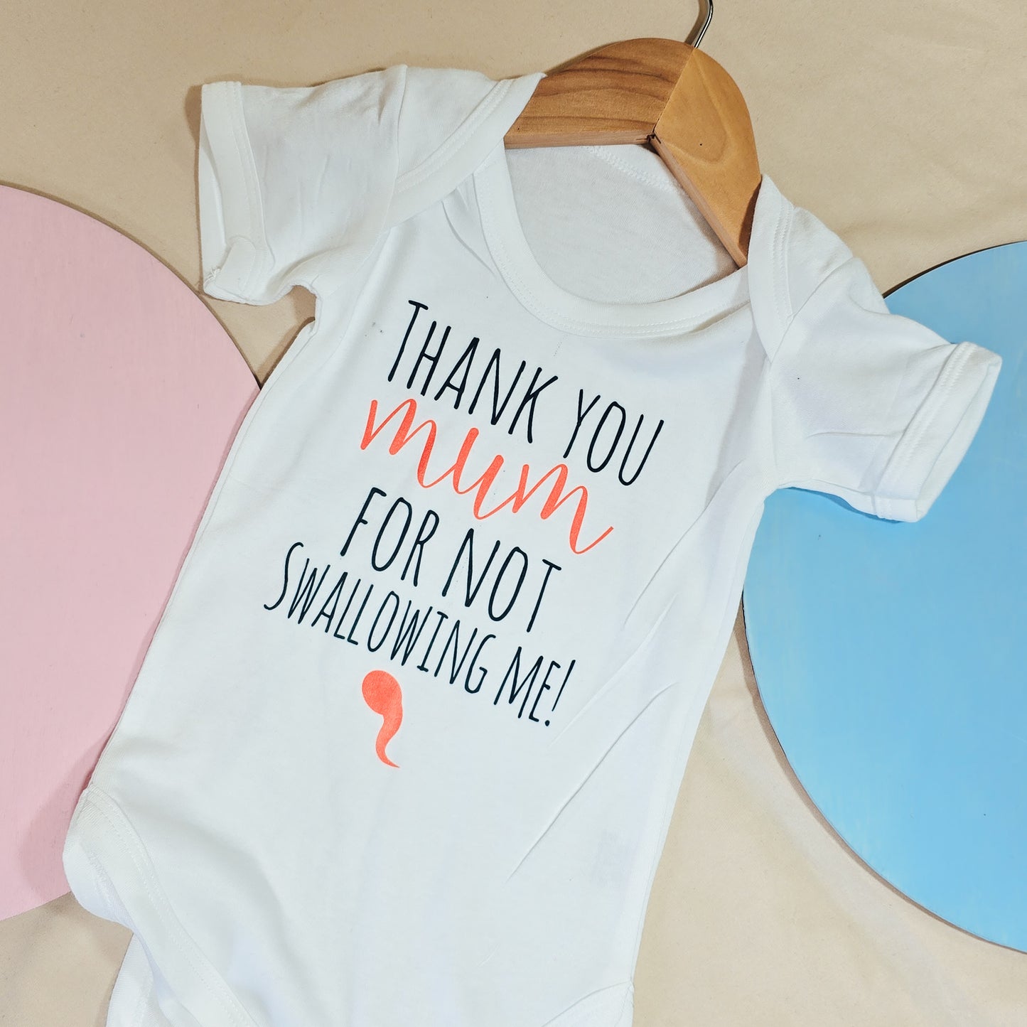A humorous baby vest featuring the phrase "Thank you mum for not swallowing me" in playful lettering. The vest is made from a comfortable blend of 65% polyester and 35% cotton, designed for newborns with snap closures for easy dressing.
