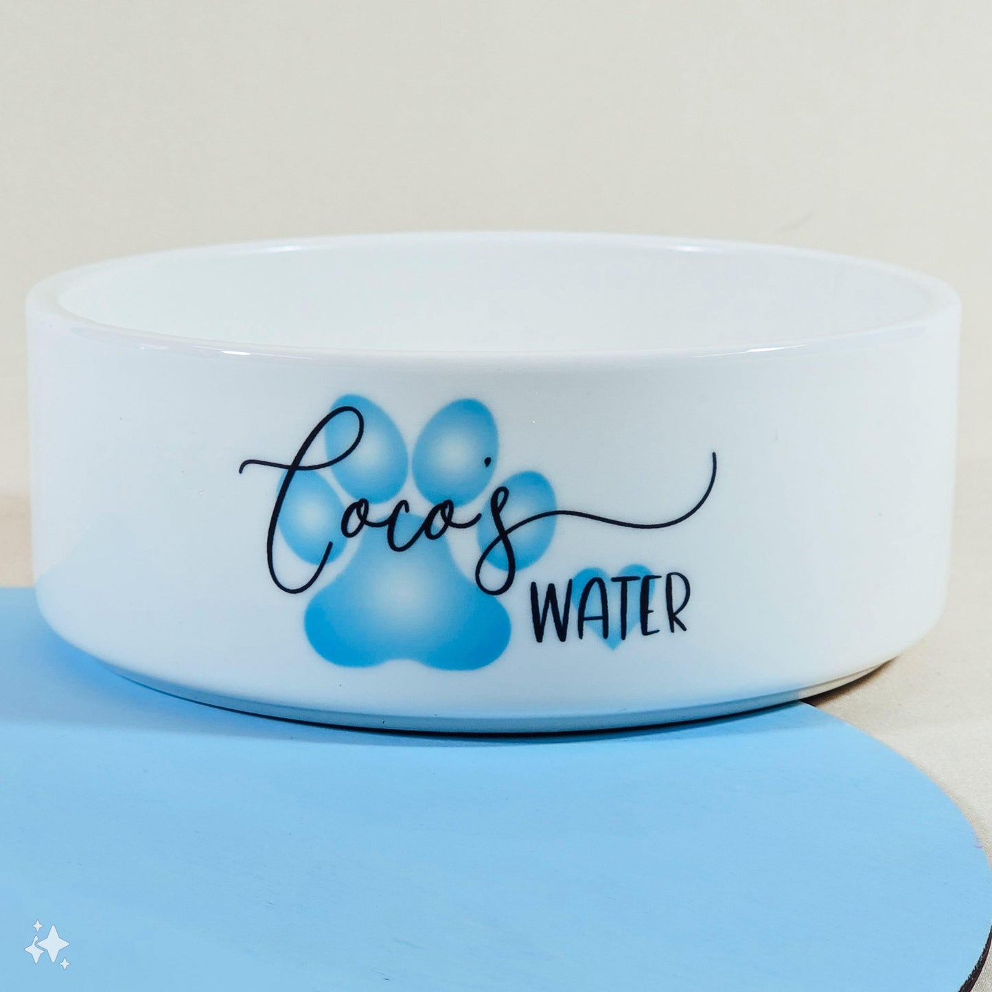 A white pet bowl with a blue paw print design, personalised with "Name's Water" or "Name's Food." The colour can be customised, and it comes in three sizes. Perfect for any pet!