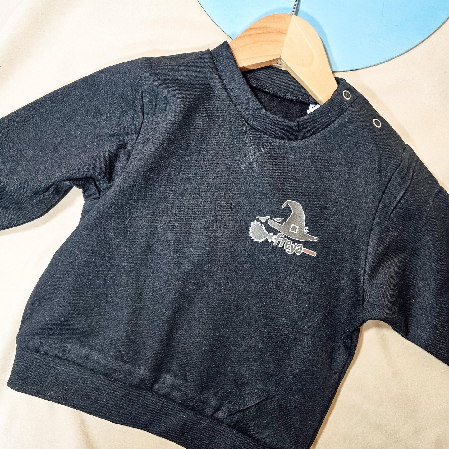 Black kids jumper featuring a witches hat and broomstick design, personalised with the child's name.