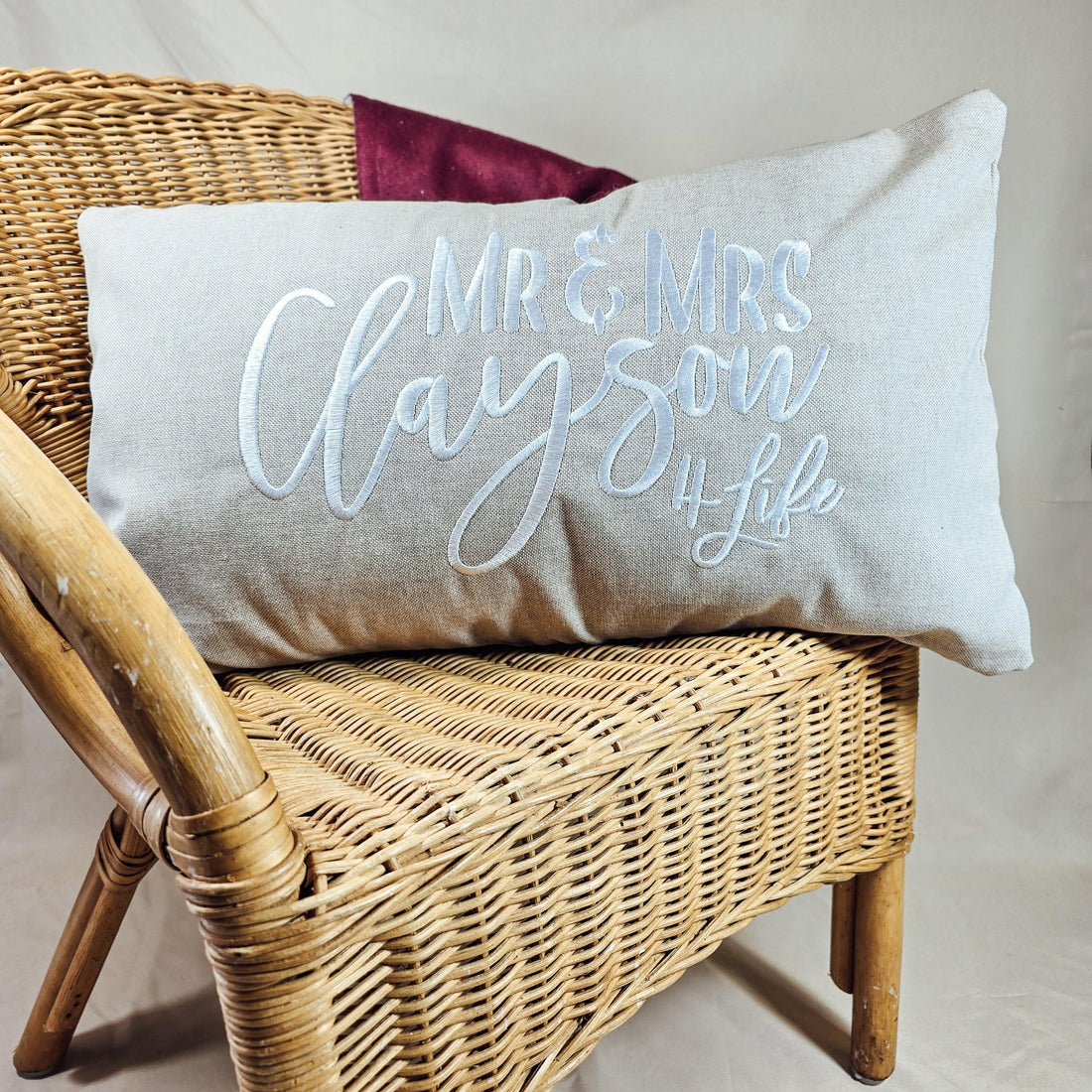 A linen cushion on a wicker chair embroidered with the couples name and '4life' for their 4th wedding anniversary