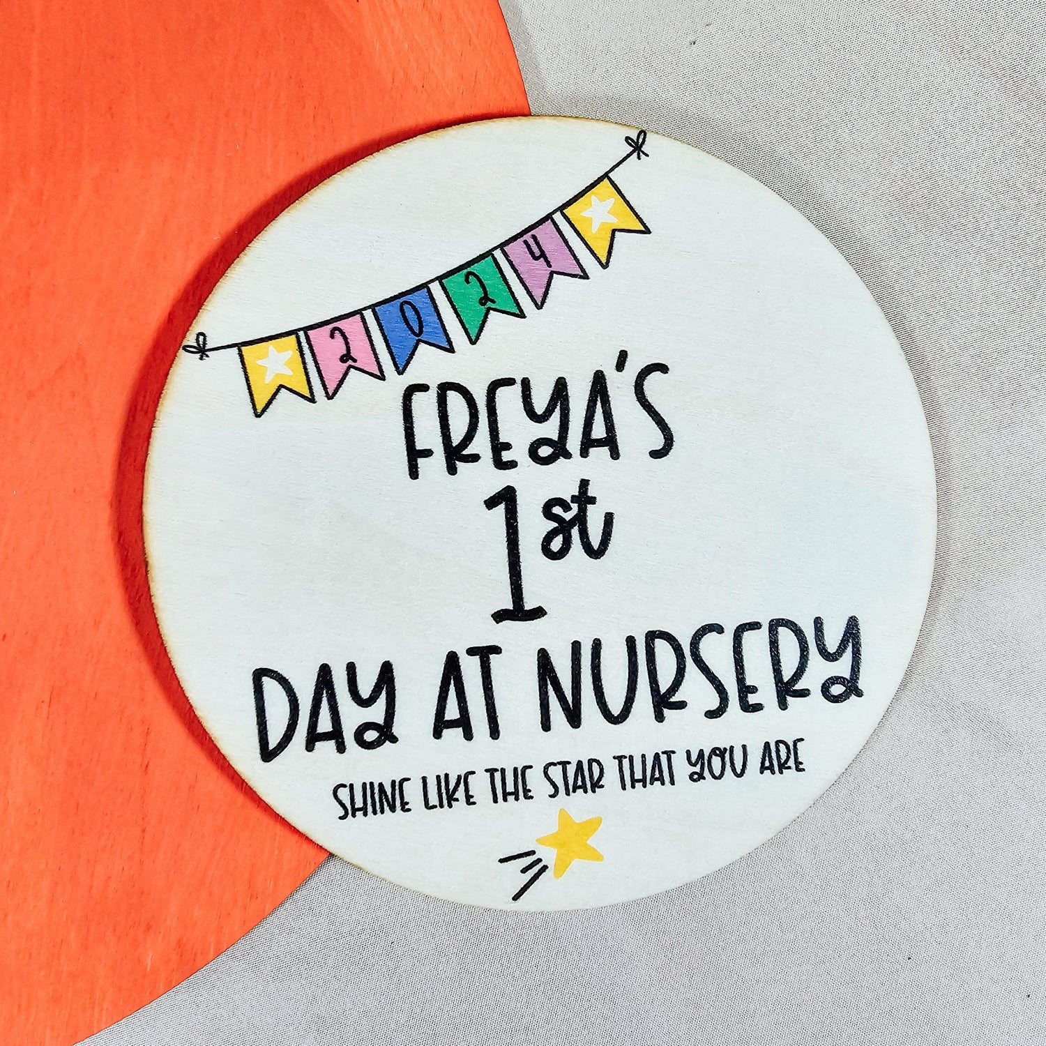 a circular wooden sign with 'names first day at nursery' on, with colourful bunting and a shooting star