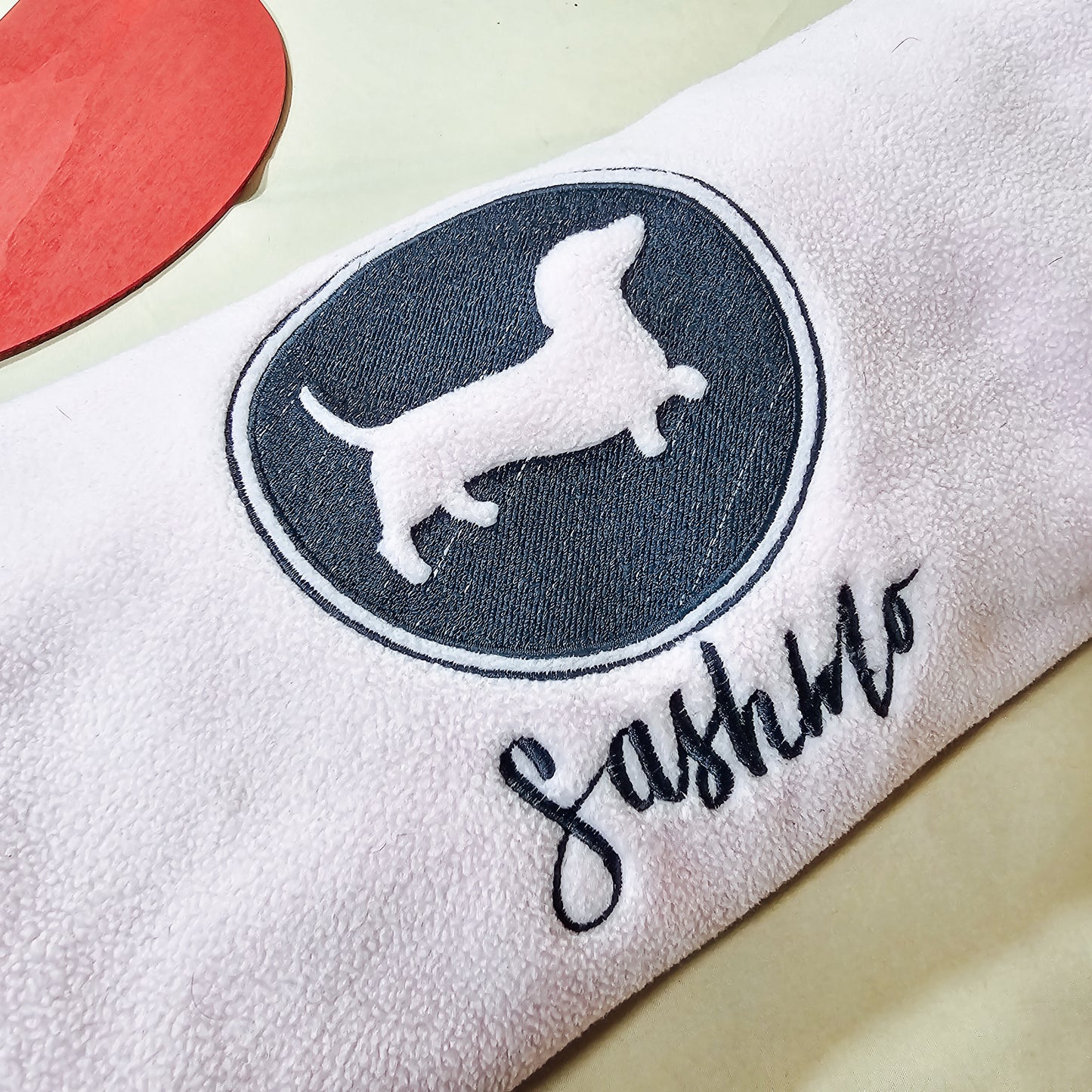 A 100x75cm fleece blanket featuring a cute dachshund embroidered design with the pet's name, available in blue or pink, perfect for dachshund lovers.