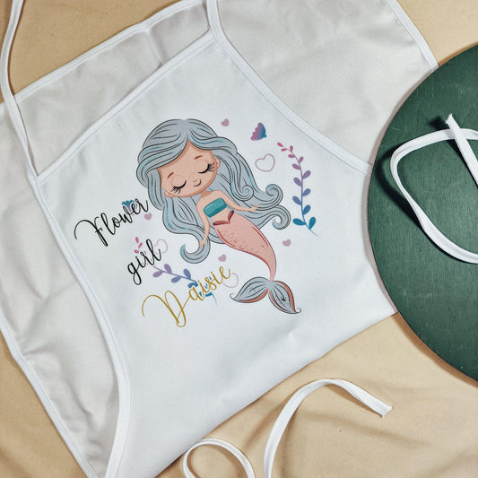 A white apron with 'flower girl' written on and a mermaid design