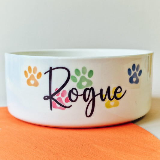 Pet bowl with rainbow-coloured paw prints behind a personalised name, available in small, medium, and large sizes, adding a vibrant touch to your pet’s feeding time.