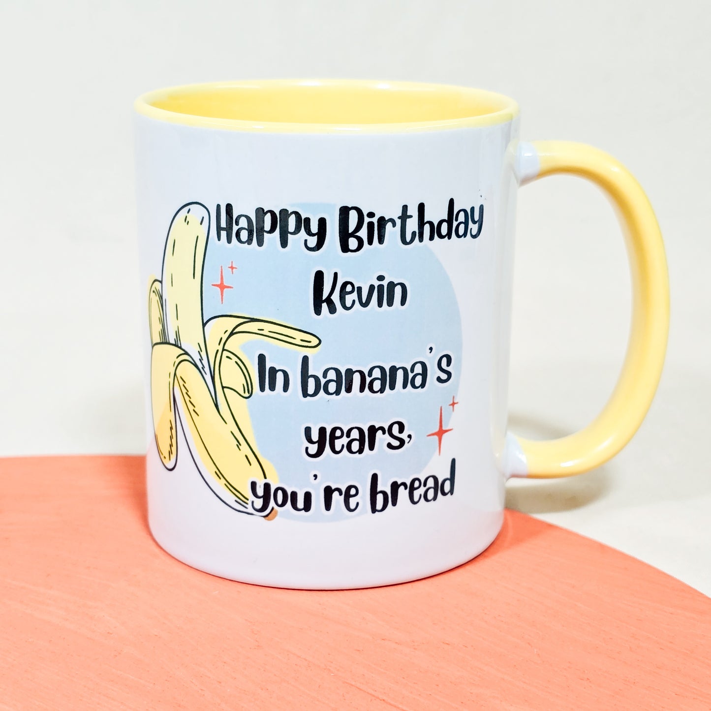 A ceramic 10oz yellow inner mug with the message "Happy Birthday [Name], in banana's years you're bread," perfect for a humorous and personalised birthday gift.