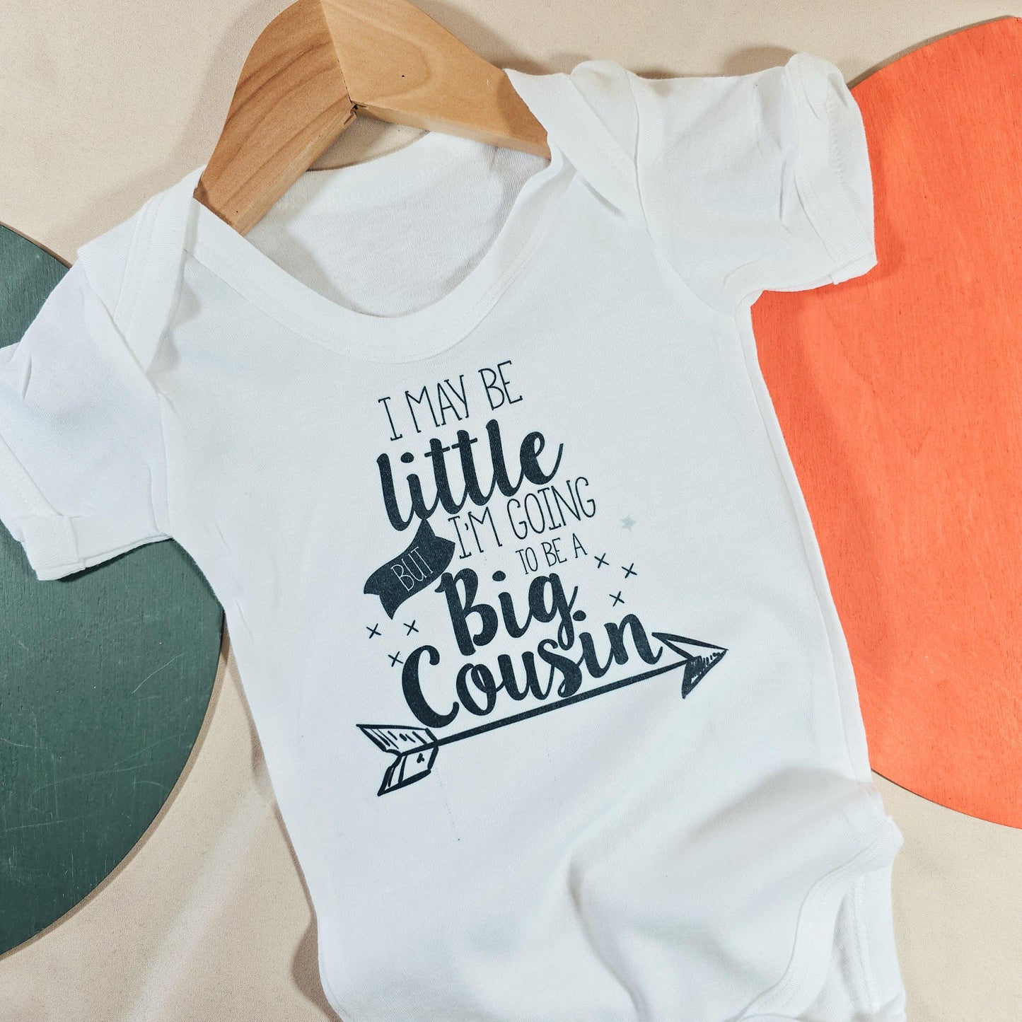 Personalised baby vest with the message "I might be little but I'm going to be a big cousin," perfect for baby announcement outfits.

