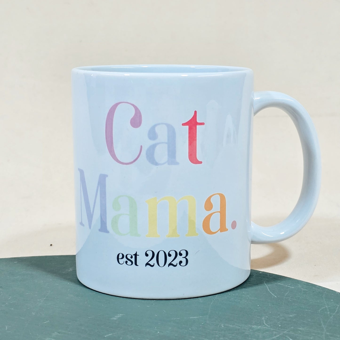 A white ceramic mug with "Cat Mama Est [Date]" in elegant script, available with a matching pet bowl in various sizes.

