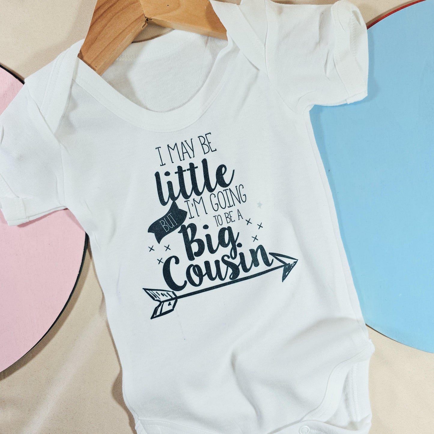 Personalised baby vest with the message "I might be little but I'm going to be a big cousin," perfect for baby announcement outfits.

