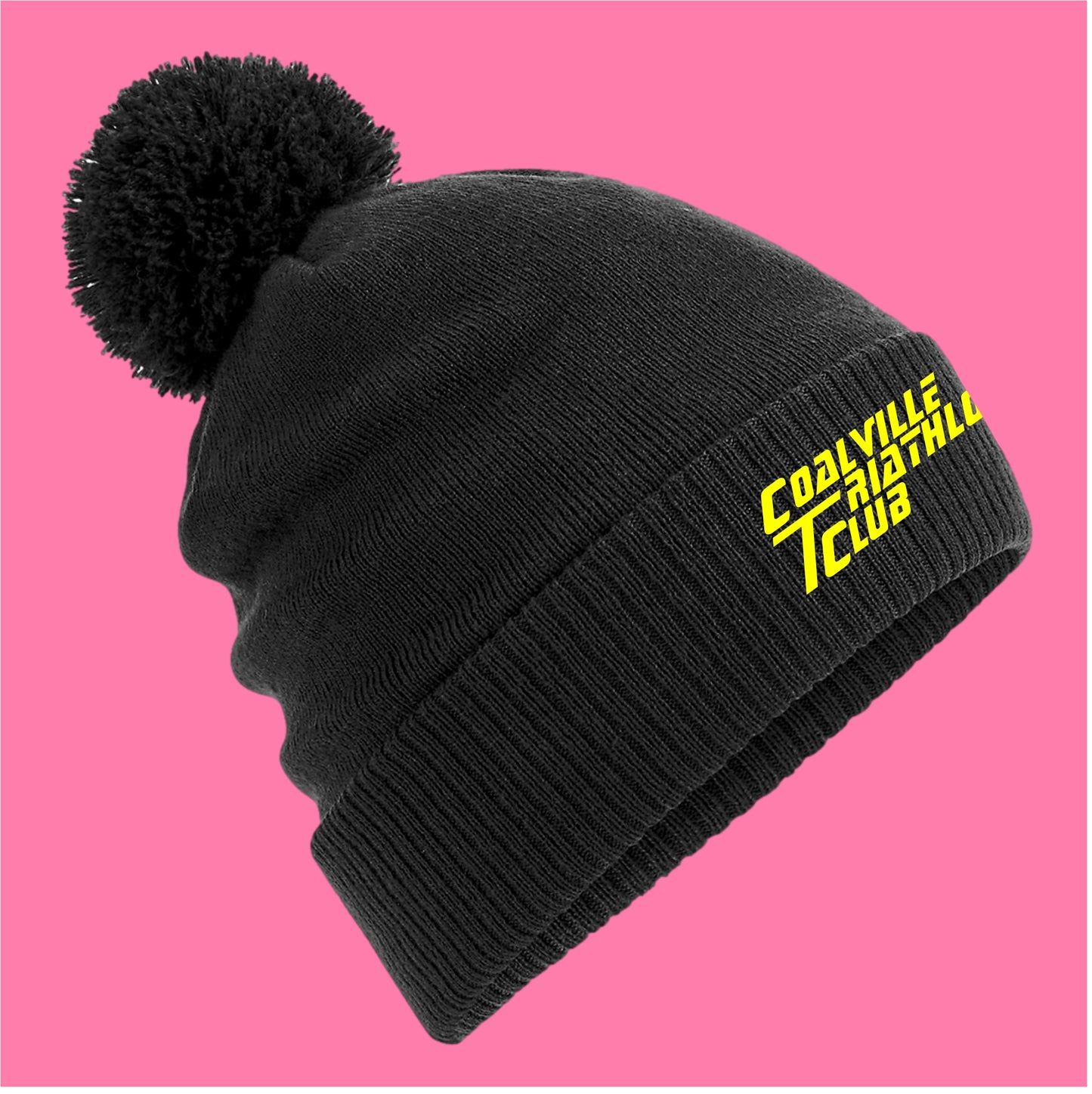 Black beanie with a pom-pom on a pink background
