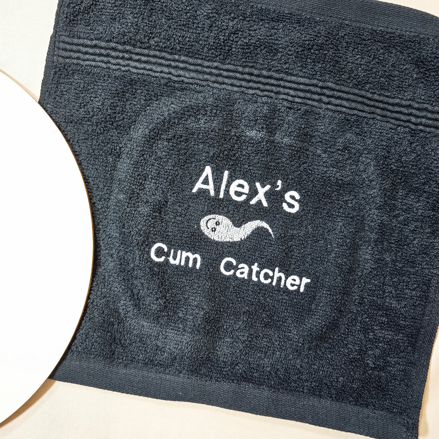 Personalised cum catcher towel, soft black fabric with a cheeky custom name, perfect for a funny, adult-themed gag gift or novelty present.
