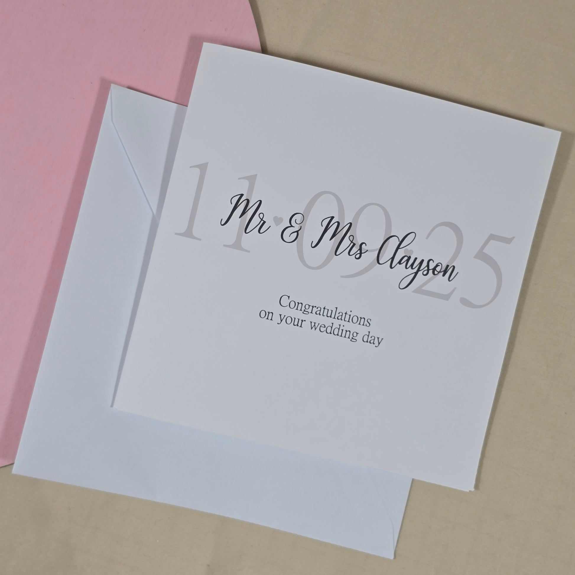Square wedding card with the message “Congratulations on your wedding day,” featuring the wedding date in the background and the couple’s new name on top.

