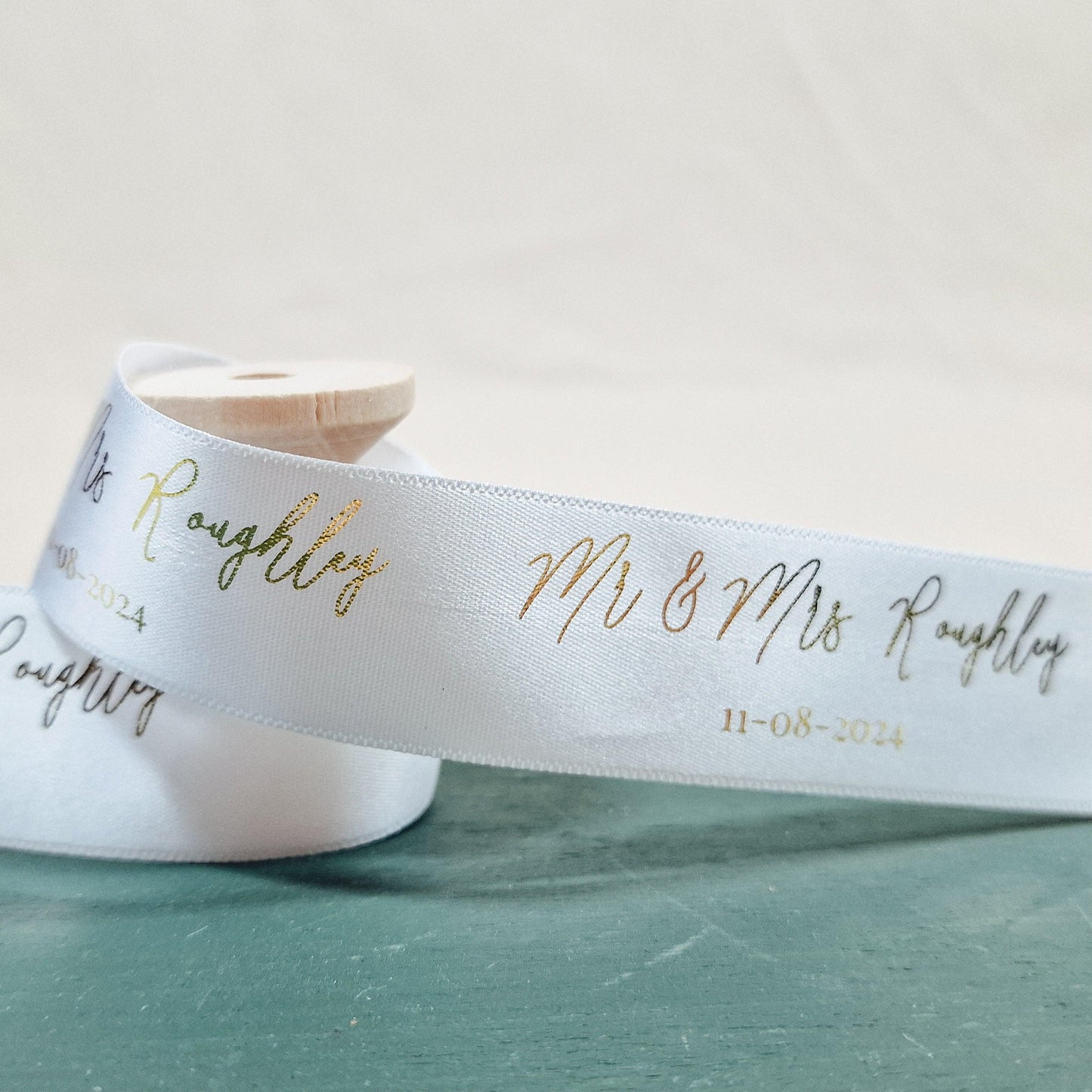 Custom wedding ribbon printed with "Mr & Mrs [Name]" and wedding date. 25mm wide, available in various colours, with options for "Mr & Mr," "Mrs & Mrs," and other titles.