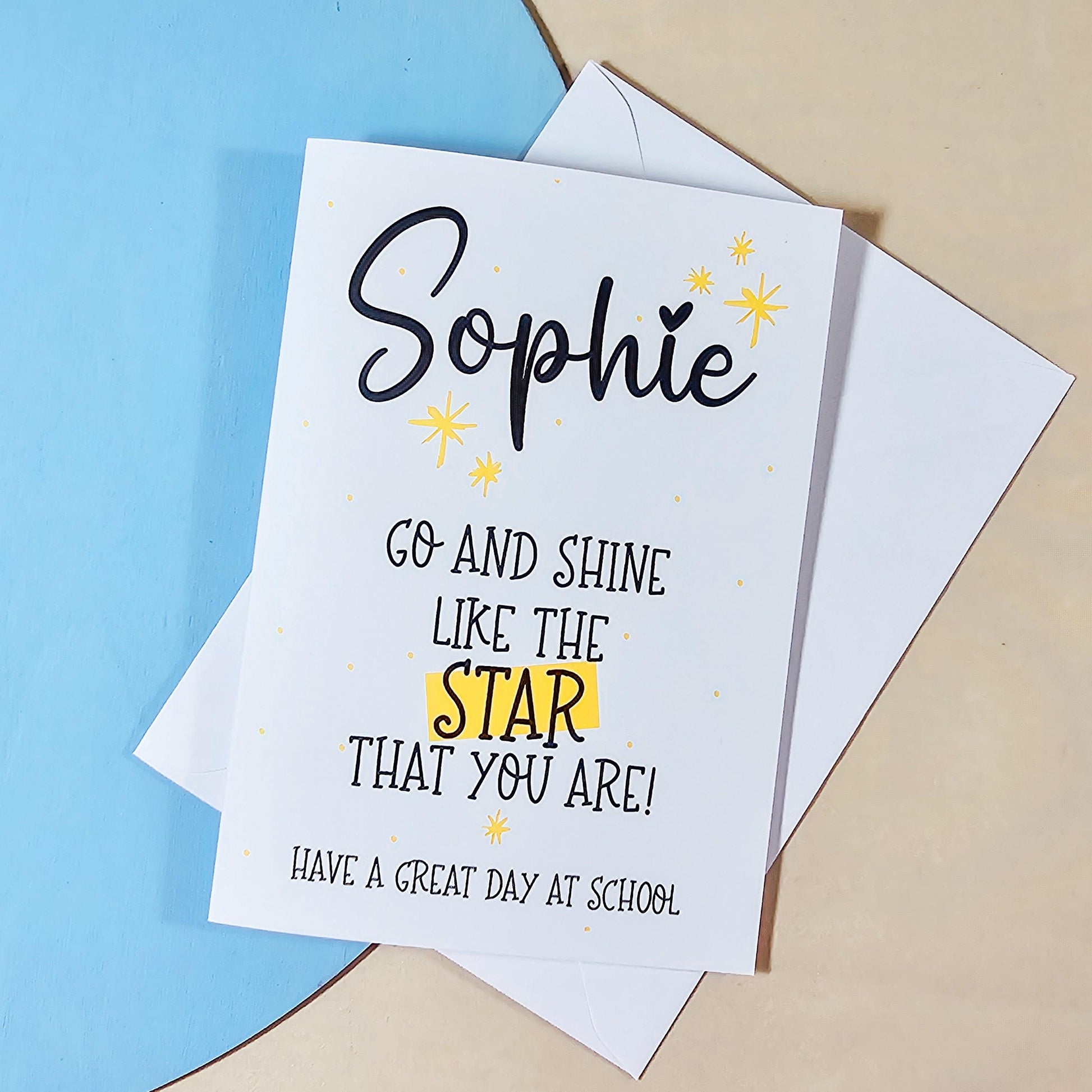 A white card with the text 'go and shine like the star that you are! Have a great day at school' with yellow start motifs on and a personalised name