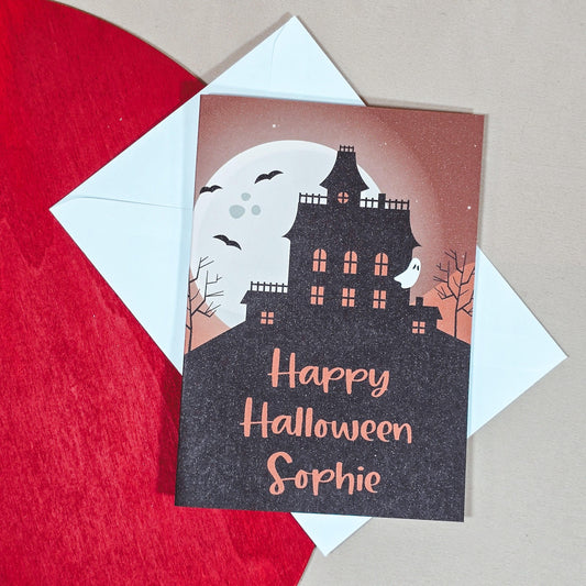 Personalised Halloween card with a haunted house design, customisable with the recipient's name, and an option to add an inside message.

