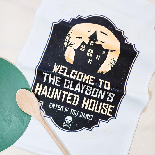 Personalised Halloween tea towel with the text "Welcome to the [Name's] Haunted House! Enter if you dare," featuring spooky Halloween designs.