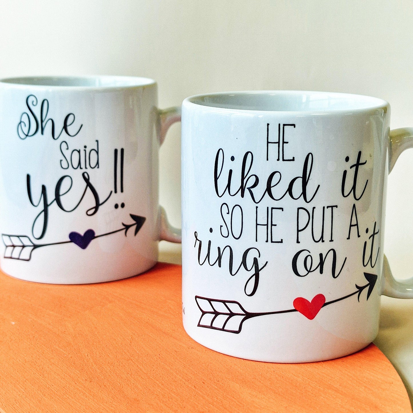 Pair of engagement mugs, one with "He Liked It So He Put a Ring On It" and "The Future Mrs [Name]", and the other with "She Said Yes" and "One Very Lucky Mr [Name]". Available in 10oz and 15oz sizes, dishwasher safe. Custom back text available.