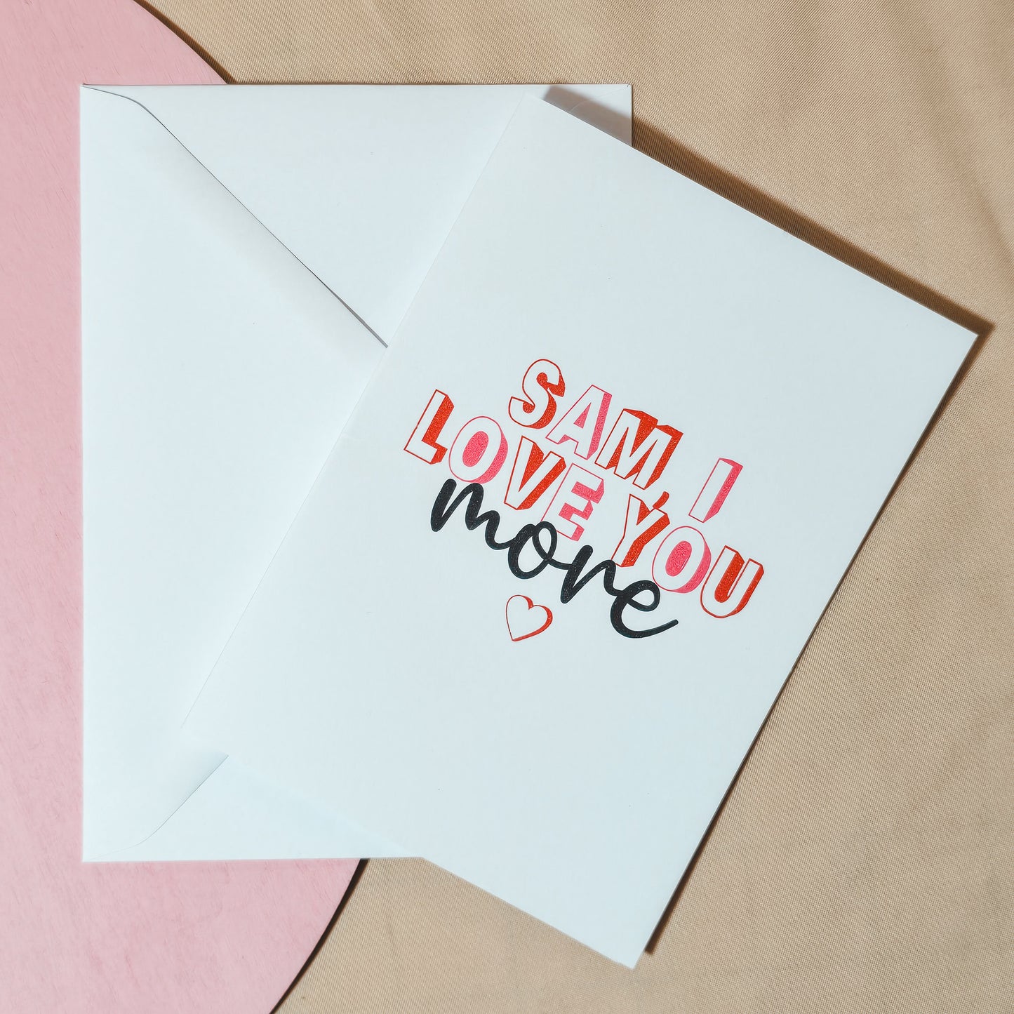 Personalised A6 card with the text "[Name] I love you more" in a romantic font, ideal for Valentine’s Day, anniversaries, or as a thoughtful gesture. Comes with a white envelope.