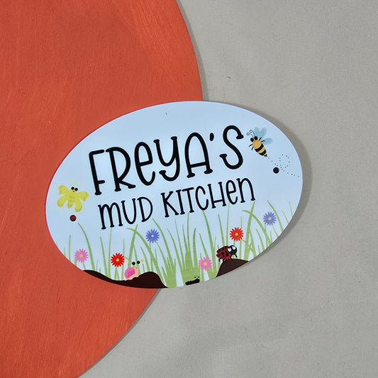Decorative sign for 'Freya's Mud Kitchen' with cartoon elements on a red and gray background.