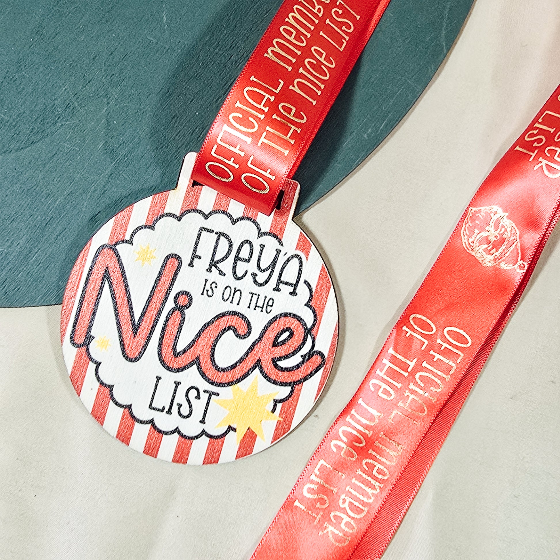 Medal with 'name is on the Nice List' text and red ribbon on a neutral background