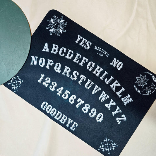 A non-slip pet mat with a Ouija board design, featuring the custom text "[Pet's Name]'s Food." The mat is 41x27cm, perfect for Halloween or adding a spooky touch to your pet's feeding area.