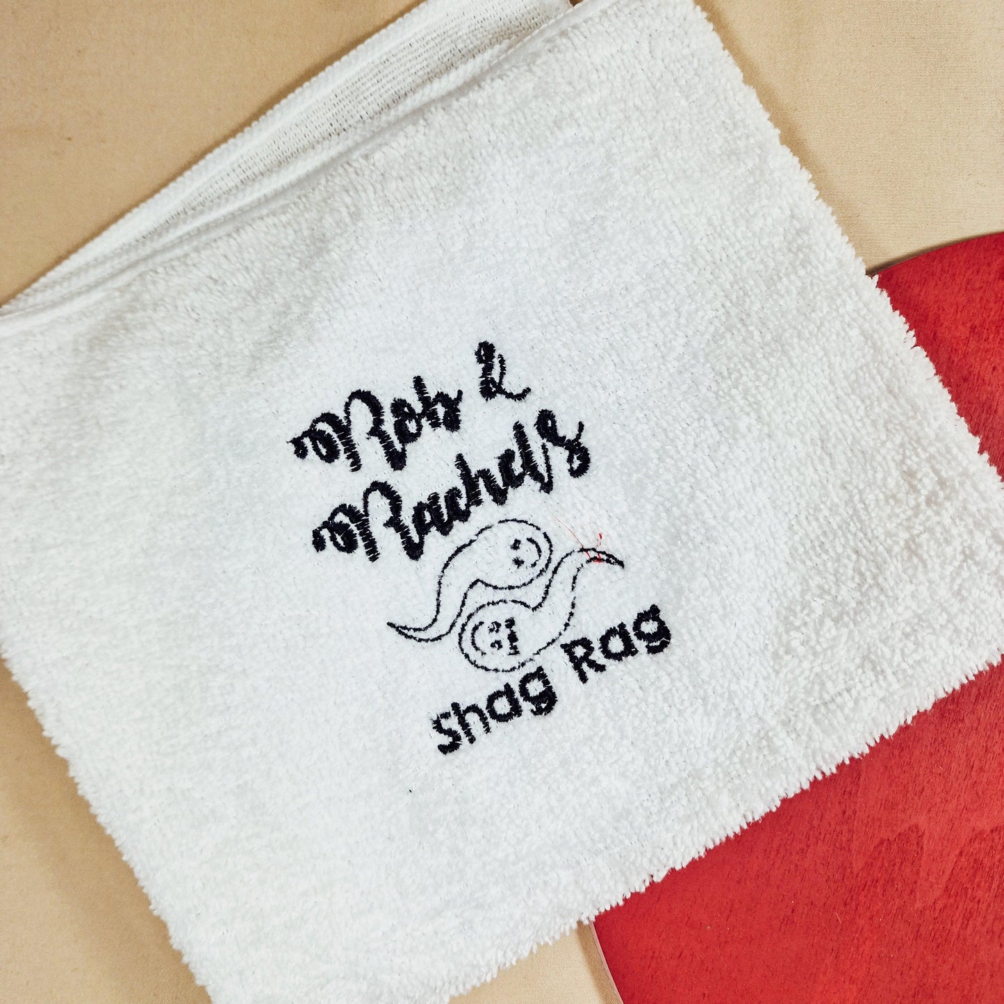 A soft towel embroidered with two playful sperm characters and the text "[Name] & [Name]'s Shag Rag," making it a funny and personalised gift for couples.