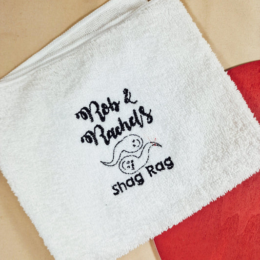 A soft towel embroidered with two playful sperm characters and the text "[Name] & [Name]'s Shag Rag," making it a funny and personalised gift for couples.