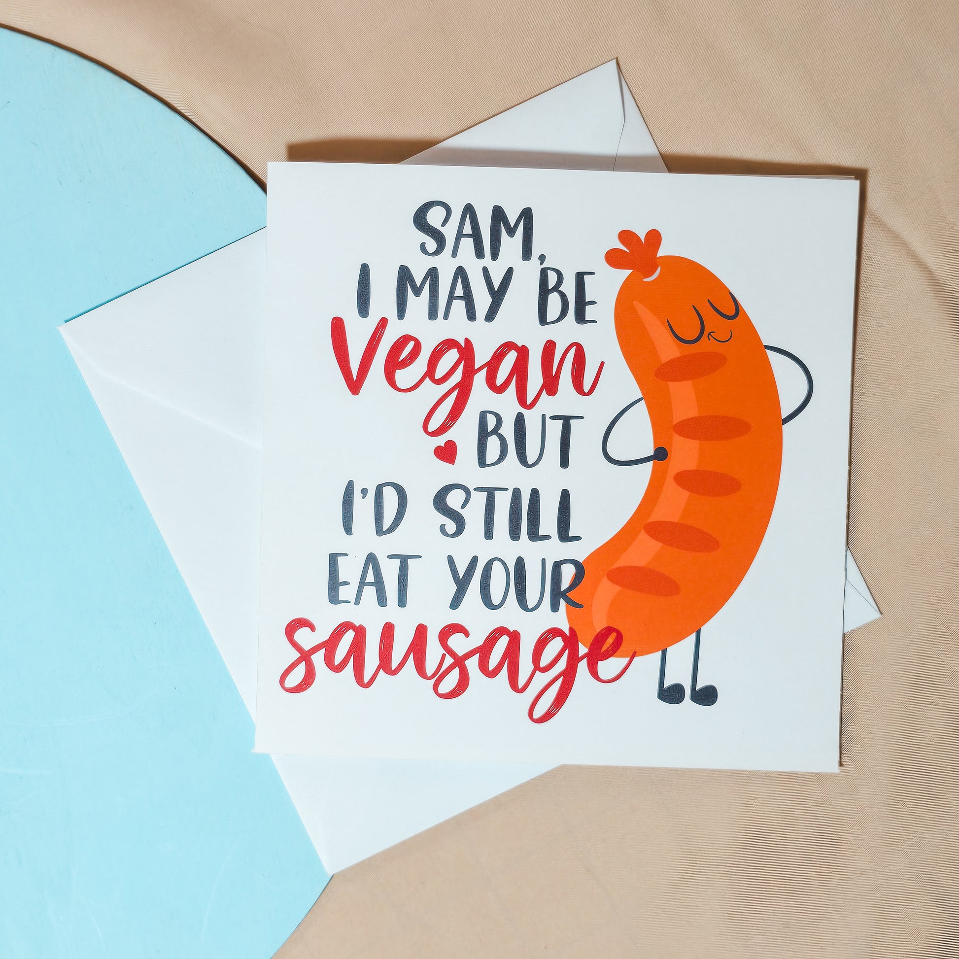 Funny vegan Valentine’s card with the text "[Name], I may be vegan, but I’d still eat your sausage" in a playful font, featuring a cheeky design. Square card with personalisation options, paired with a white envelope.