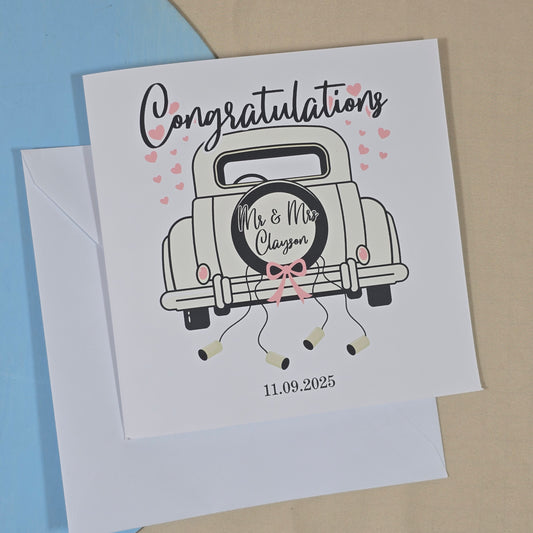 Square wedding card featuring a car illustration with "Congratulations" above, custom couple names on the back of the car, and personalised wedding date underneath.

